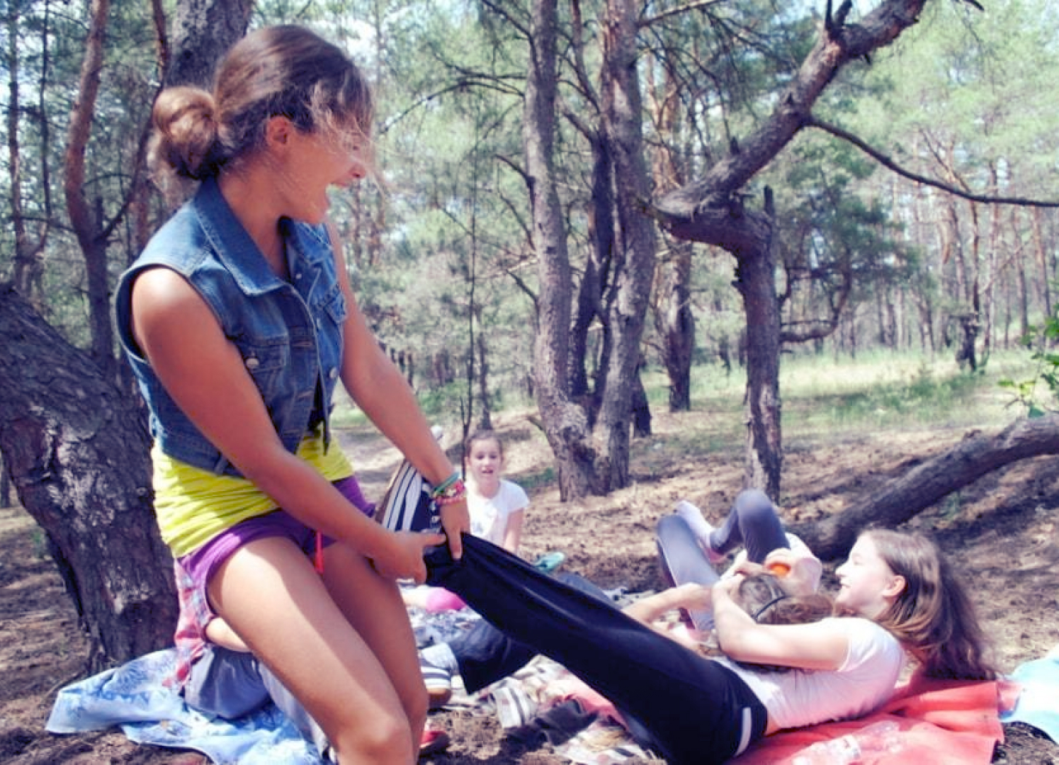 Учні старшої школи граються в лісі на покривалах під час літнього табору