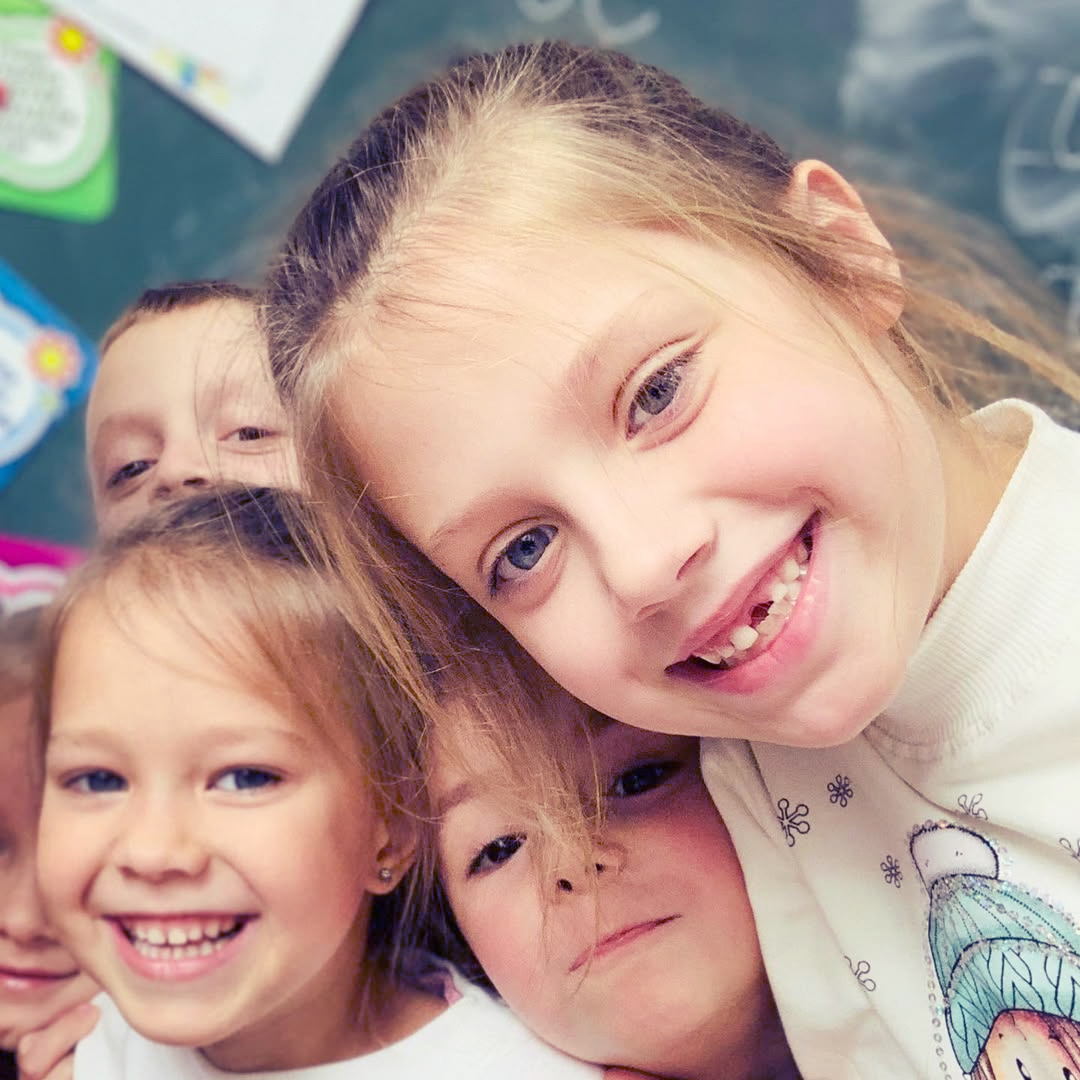 Діти молодшої школи в класі посміхаються на камеру