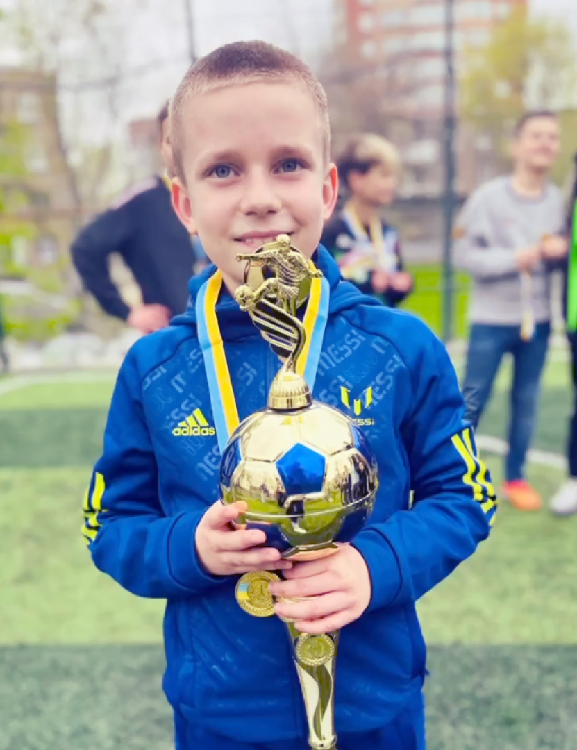 Хлопчик тримає кубок і має медаль із змагань по футболу