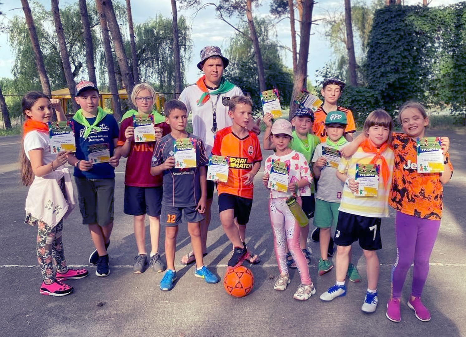 Діти на спортивних змаганнях разом із тренером на вулиці влітку під час шкільного табору